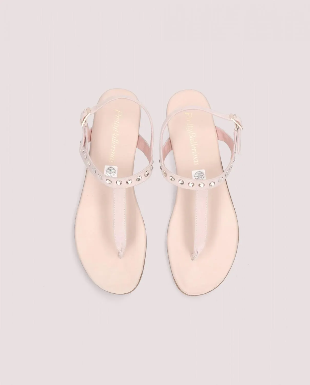 Sandalia modelo Judy en ante suave rosa maquillaje con tira cubierta de cristales Swarovski, suela de goma y plantilla de piel.